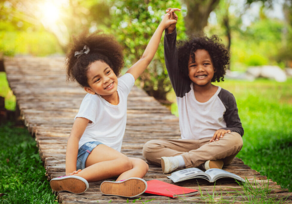 Happy little boy and girl in the park. Two African American children together in the garden.