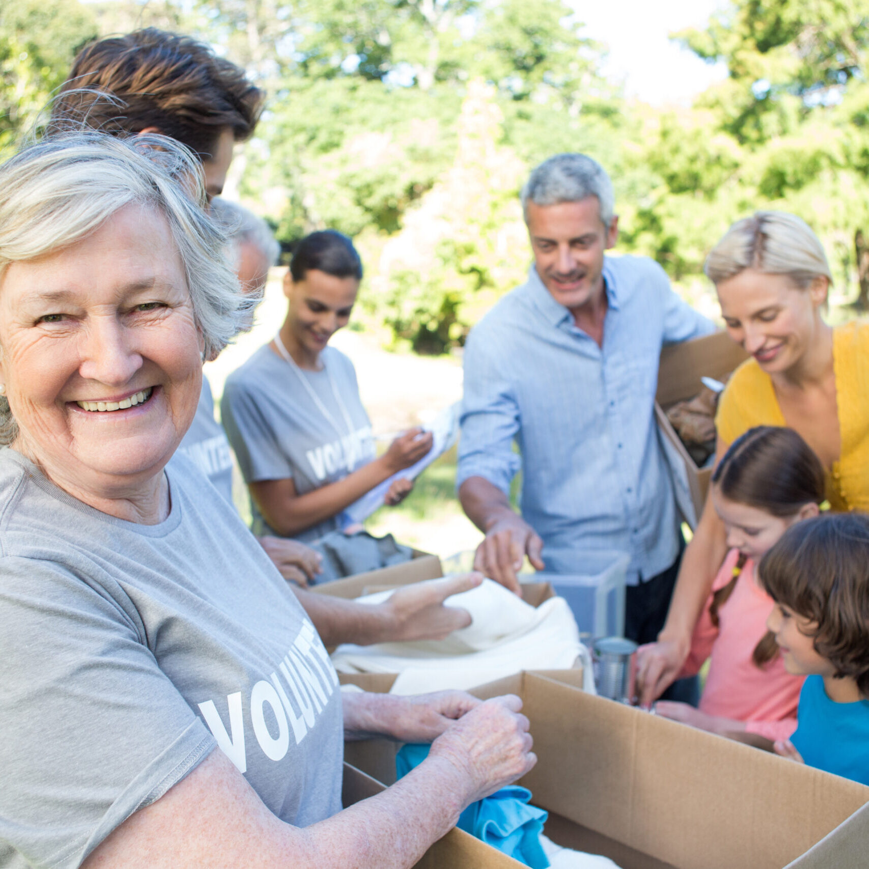 Happy volunteer family separating donations stuffs on a sunny day Happy volunteer family separating donations stuffs on a sunny day